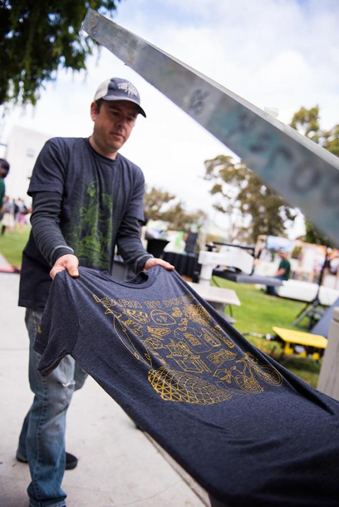 A man runs a t-shirt through a printing machine