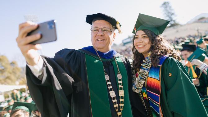 President Armstrong and a new graduate take a selfie together