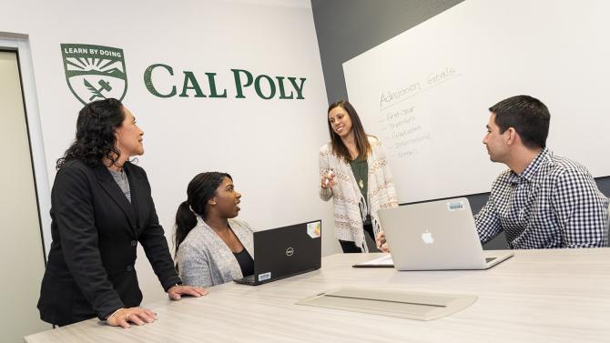 Four staff members work together on a project at a white board