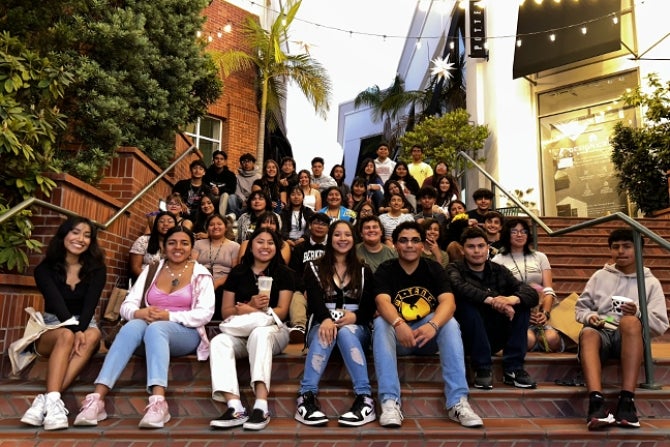 A group of Upward Bound high school students pose for a photo seated on the steps of a downtown San Luis Obispo shopping location