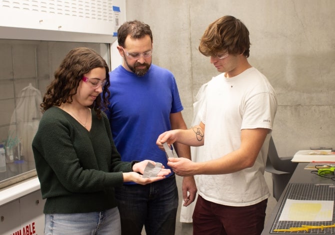 Chemistry Professor Phil Costanzo with Cal Poly students in a university lab discussing a D-glue product