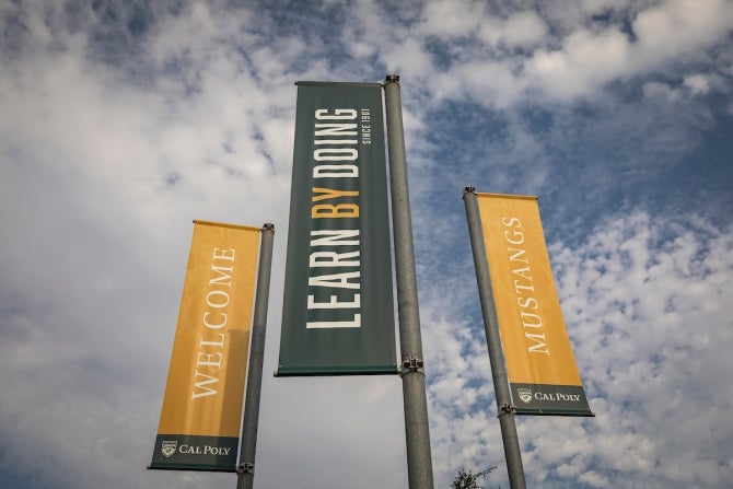 A trio of Cal Poly welcoming banners under a partly cloudy sky