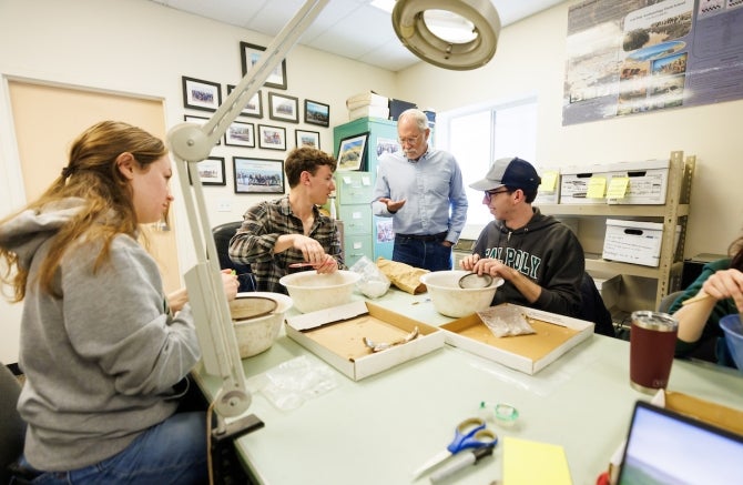 Students sit around a table cleaning unearthed Yoshida family artifacts