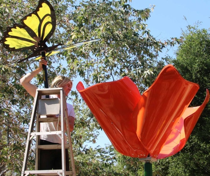 A student assembles a poppy and butterfly sculpture at the SLO Botanical Garden
