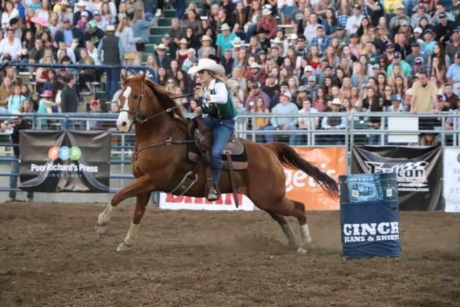 A female member of the Cal Poly Rodeo Team rides a quarterhourse on a temporary rodeo arena at Spanos Stadium