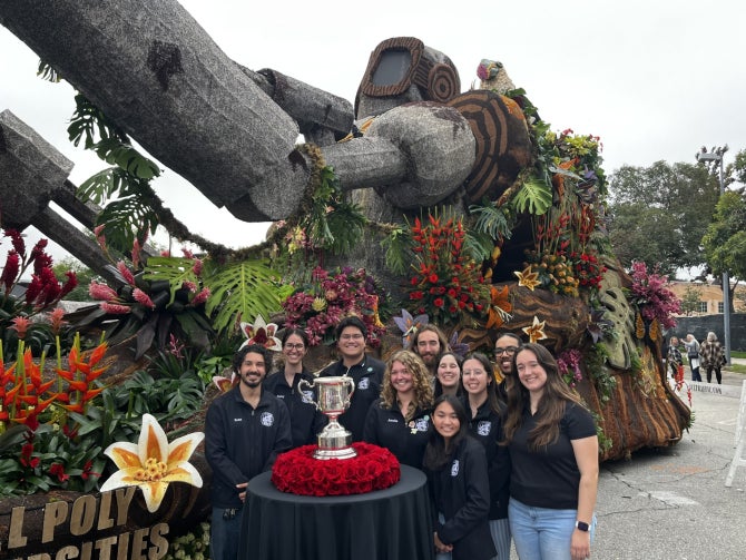The executive team of Cal Poly Rose Float stand w the Sweepstakes Award in front of the Jungle Jumpstart float