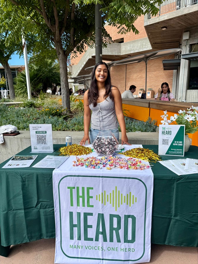 A HEARD Student stands at an information table in the University Union