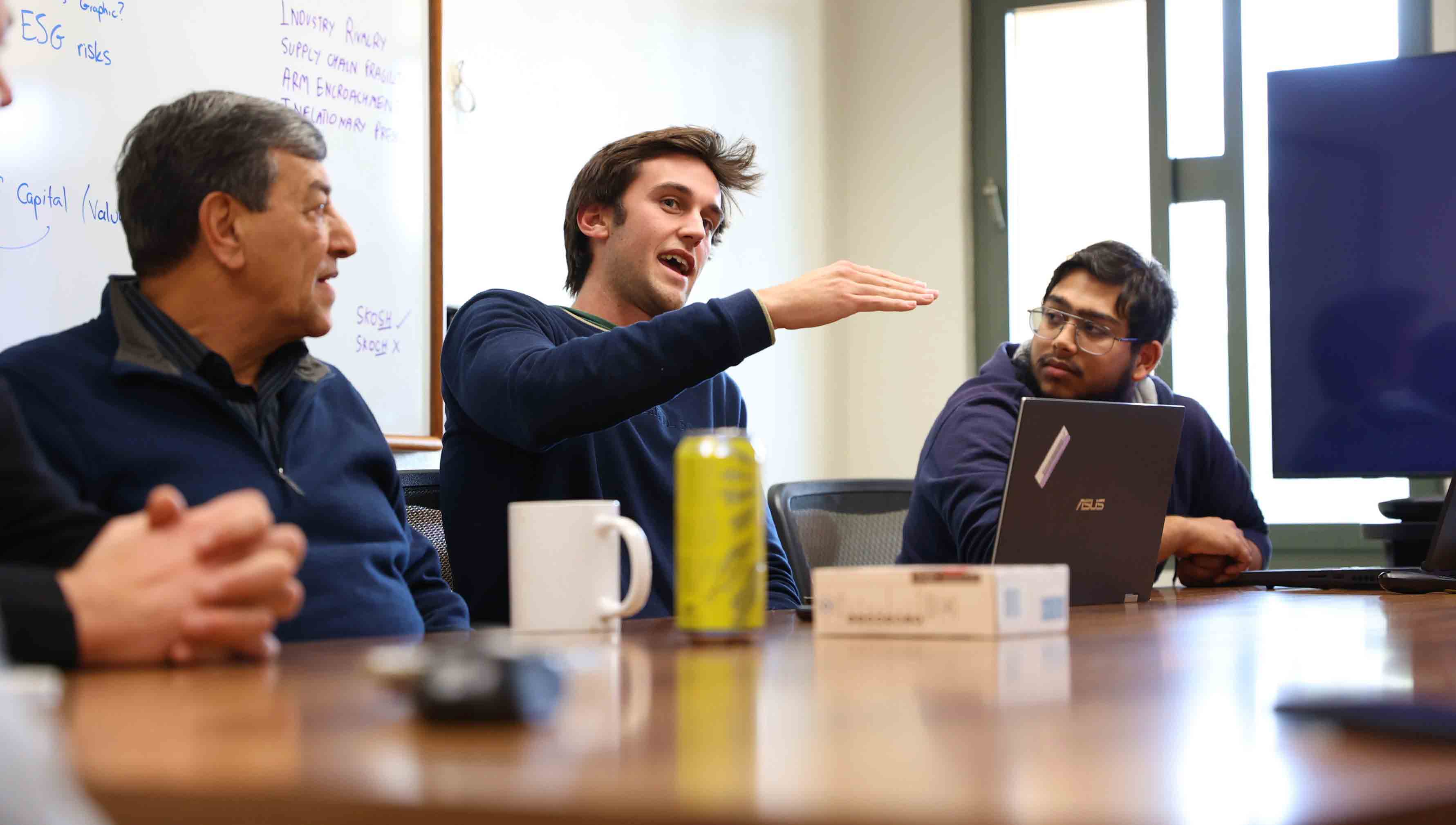 Students gathered around a table discuss their research