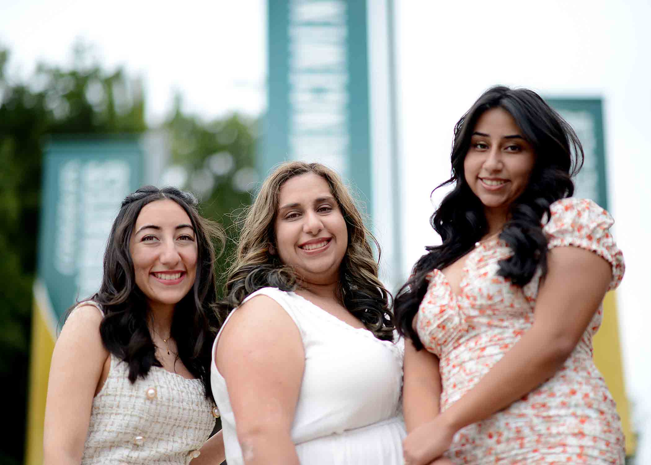 The Arredondo sisters, Erica, Stephanie and Clarissa, stand in front of the Cal Poly University welcome banners