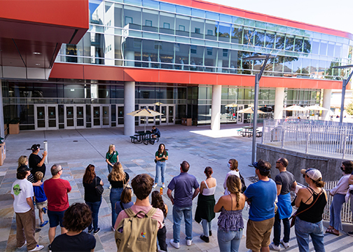 Two Poly Rep students describe the Recreation Center facility rising behind them during a tour to high school students and their parents