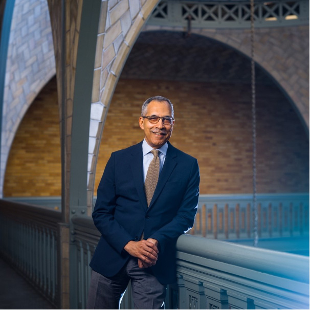 Claude Steele leaning against brick wall