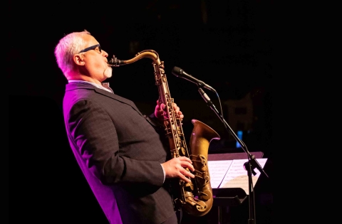 Arthur White plays the saxophone on stage