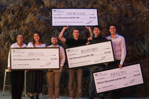 Representatives of the four startups display large checks totalling $35,000