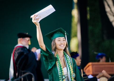 A 2023 College of Liberal Arts graduate waves to the crowd from the stage_photo by Joe Johnston