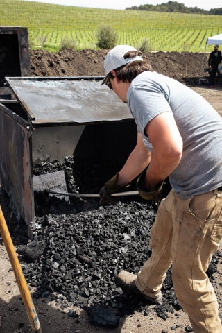 A student tends biochar, a form of charcoal made from organic wastes used as a fertilizer