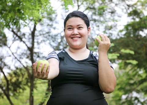  A smiling woman does toning exercises using her arms while outside