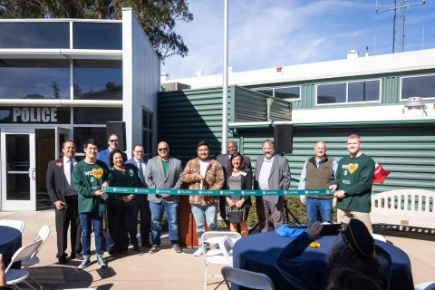 A Cal Poly student-veteran snaps the scissors with a dozen supporters at the ribbon cutting celebrating the dedication of the new center for military-connected students
