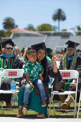 Ashlee Hernandez sits with her son on the field at Spanos Stadium for  Commencement
