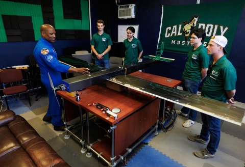 NASA astronaut and Cal Poly Alumnus Victor Glover looks at an autonomous research plane with an 11-foot wingspan while interacting with four students who built the plane.