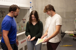 Chemistry Professor Phil Costanzo with Cal Poly students in a university lab discussing a D-glue product