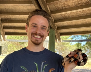 Project Manager Owen Bachhuber holds a milksnake