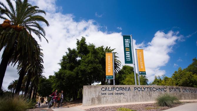 Entrance with a sign stating California Polytechnic State University and banners that say Welcome Mustangs and Learn by Dl