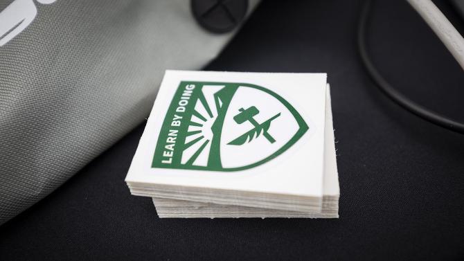 Stack of stickers of the Cal Poly shield sits on a table.