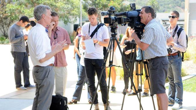 A group of people with camera record Bill Nye speaking.