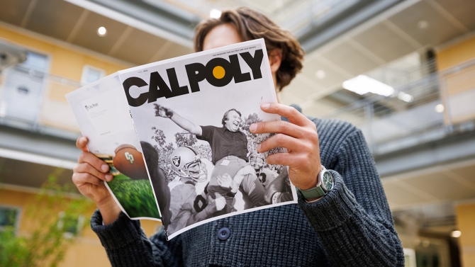 A person reads an issue of the Cal Poly Magazine featuring John Madden on the cover