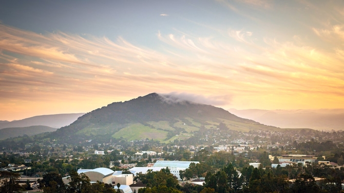 Pastel sunset colors play in the clouds in a campus landscape from the hills behind Cal Poly